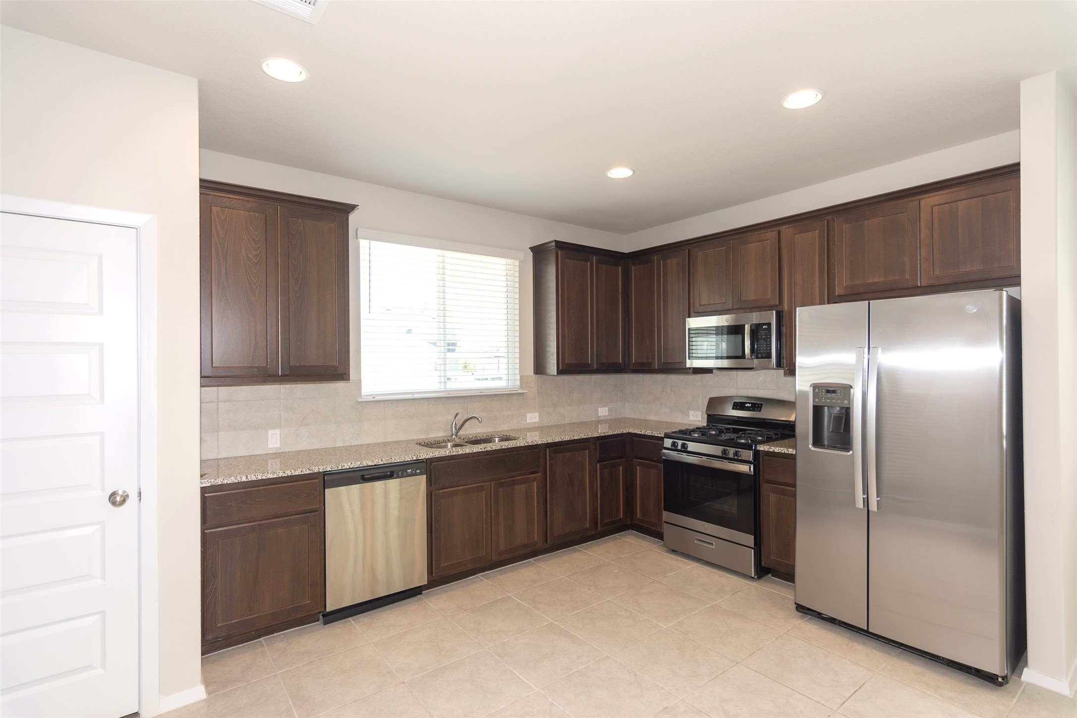 350 Fabion Street Kyle, TX 78640 - Photo 9 of 33 a kitchen with stainless steel appliances granite countertop a sink and a refrigerator