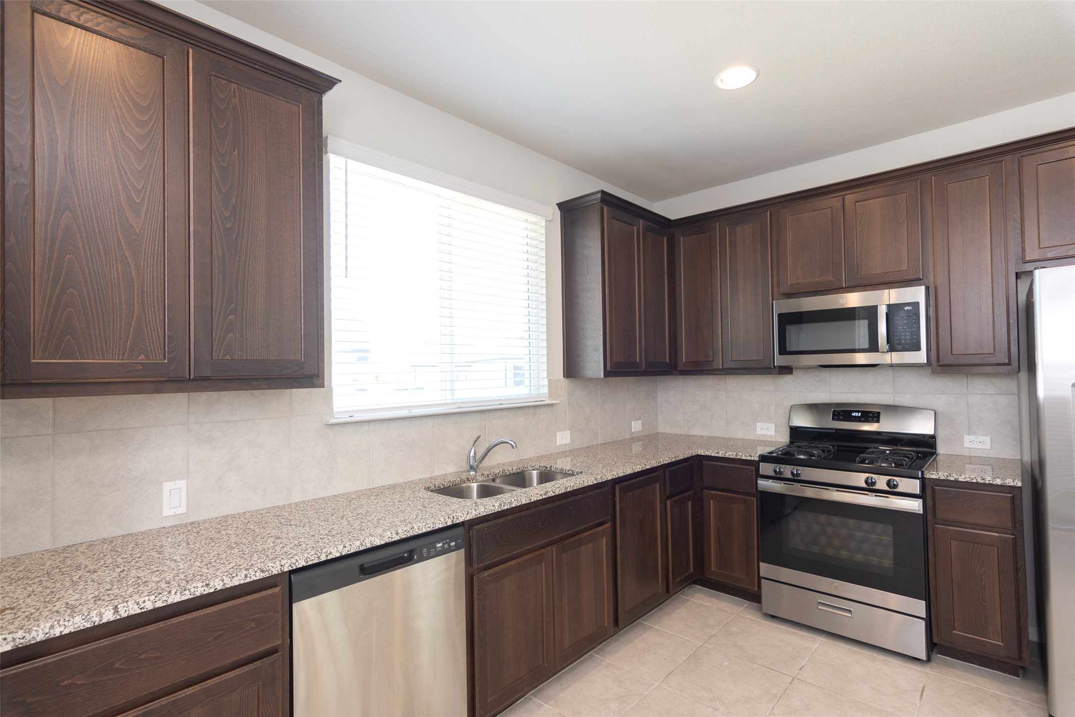 350 Fabion Street Kyle, TX 78640 - Photo 10 of 33 a kitchen with stainless steel appliances granite countertop a sink dishwasher a stove and a microwave oven with cabinets