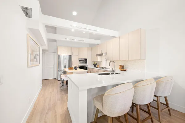 a kitchen with stainless steel appliances a sink a stove and white cabinets