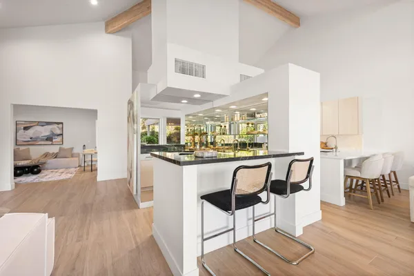 a dining hall with stainless steel appliances kitchen island granite countertop a dining table chairs and a large window