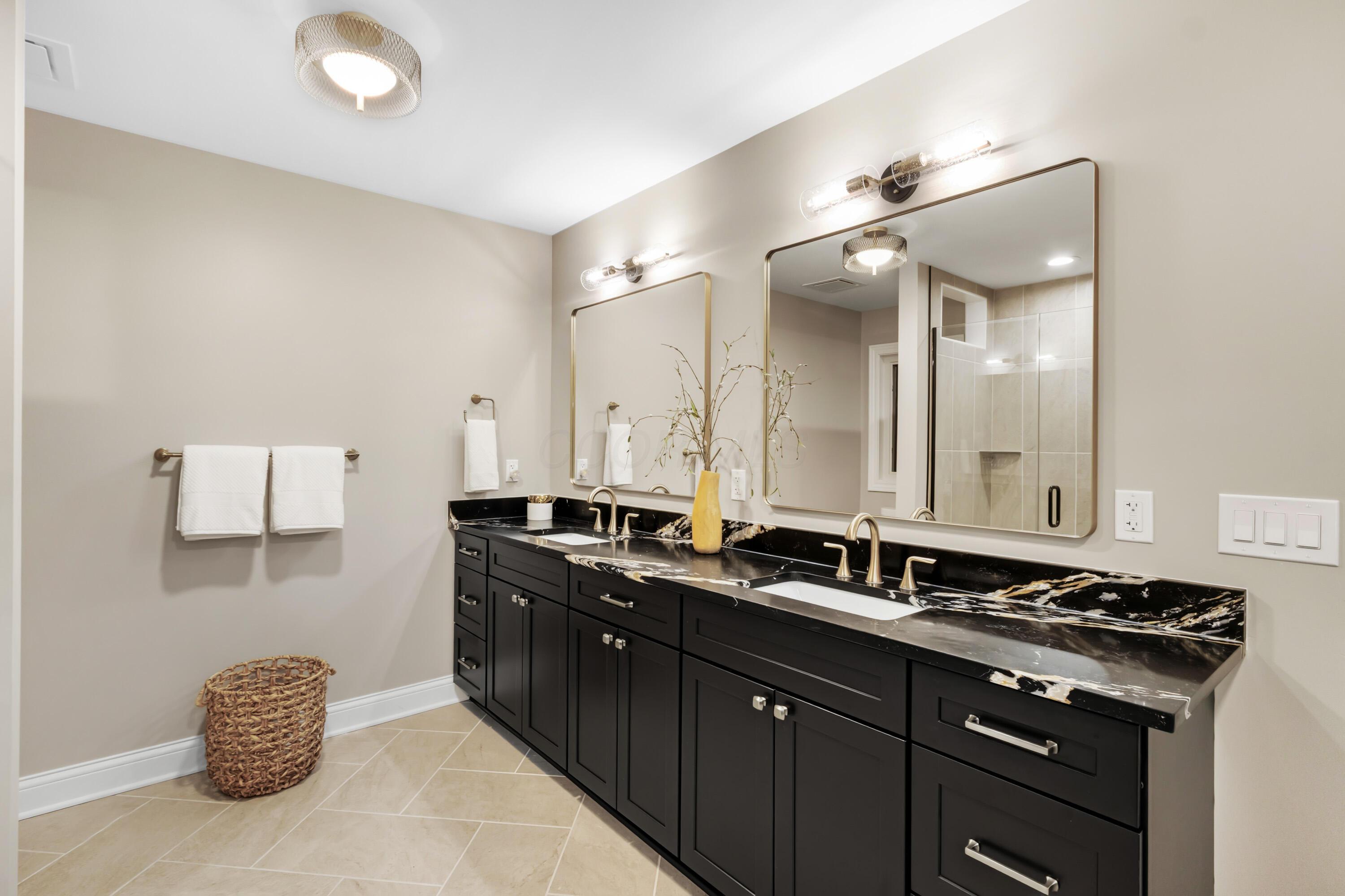 1560 Carriage Road Powell, OH 43065 - Photo 38 of 73 Dual vanity with dark cabinetry, quartz countertops, undermount sinks, and wall-mounted light fixtures