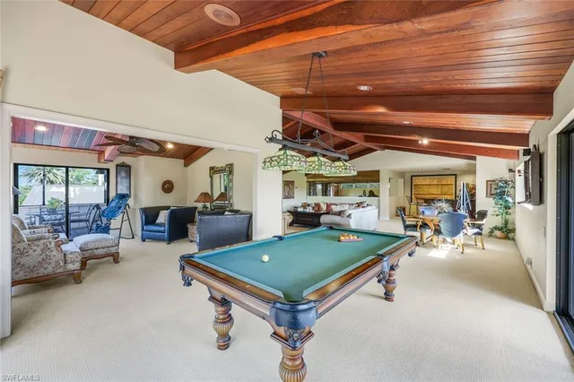 a living room with furniture pool table and large windows