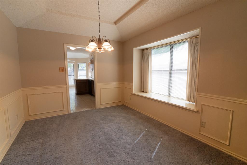 2028 Falcon Ridge Drive, Unit B Carrollton, TX 75010 - Photo 6 of 11 Unfurnished dining area featuring a decorative wall, healthy amount of natural light, a chandelier, a wainscoted wall, and a textured ceiling