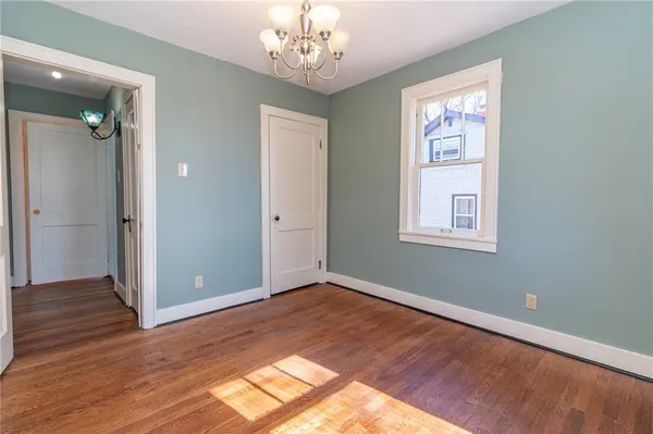 an empty room with wooden floor chandelier and windows