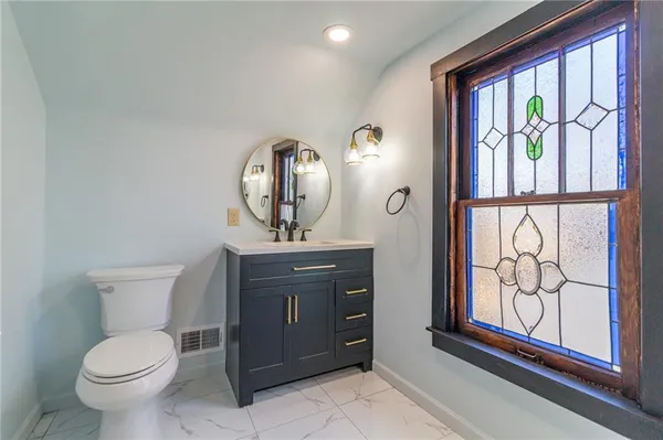 a bathroom with a toilet a sink and large window