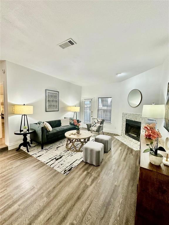 7340 Skillman Street, Unit 405 Dallas, TX 75231 - Photo 1 of 18 Living area featuring wood-finish flooring, a tiled fireplace with a dark insert, recessed lighting, and white baseboards