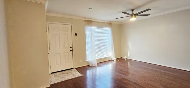 a view of a hallway with wooden floor a kitchen space with a refrigerator and a window