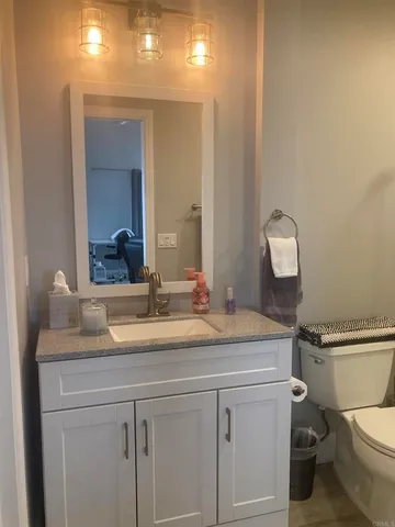a bathroom with a granite countertop sink mirror vanity and toilet