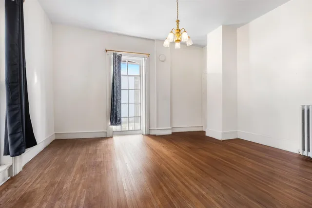 an empty room with wooden floor and window