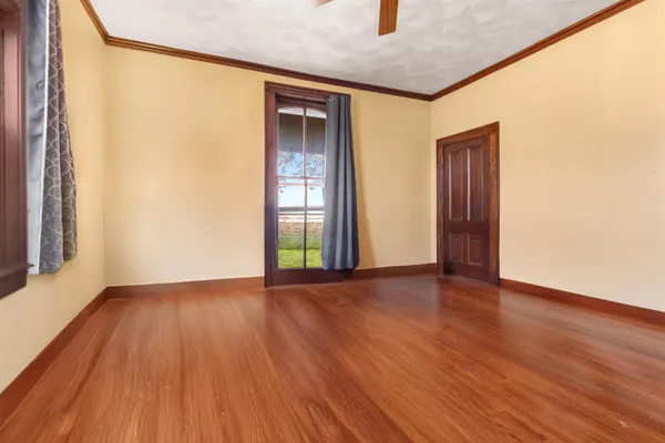 a view of an empty room with wooden floor and a window