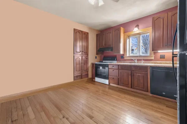 a kitchen with stainless steel appliances granite countertop a stove a sink dishwasher and a refrigerator with wooden floor