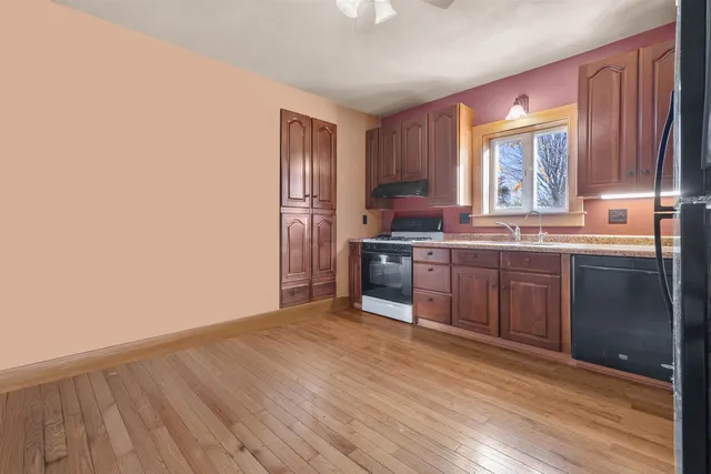 a kitchen with stainless steel appliances granite countertop a stove a sink dishwasher and a refrigerator with wooden floor