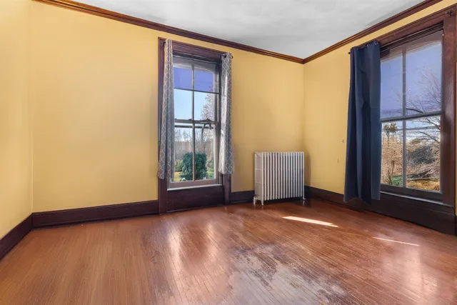 a view of an empty room with a window and wooden floor