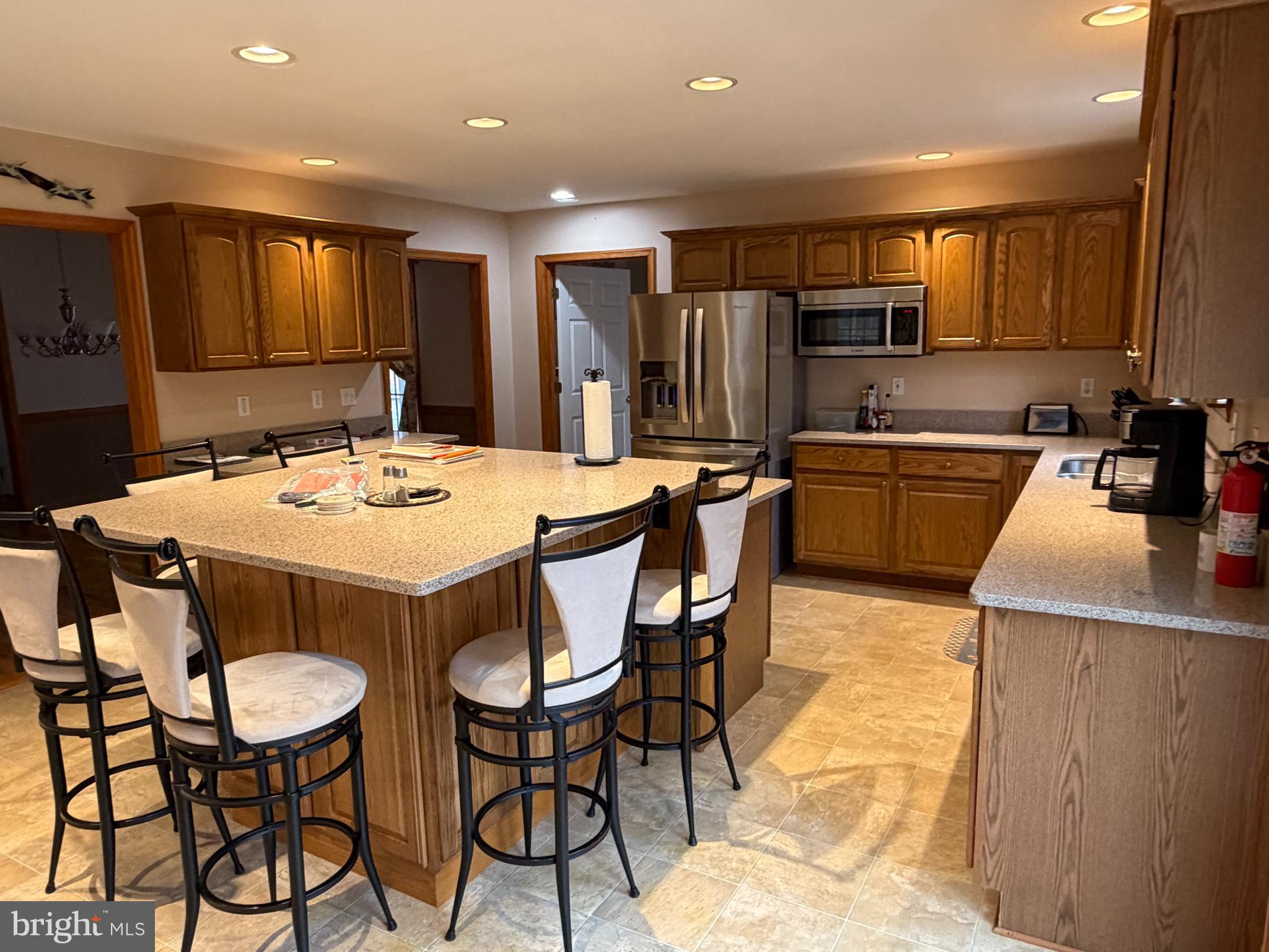 8664 Mitchell Road Denton, MD 21629 - Photo 7 of 22 a kitchen with stainless steel appliances kitchen island granite countertop a kitchen island and chairs in it