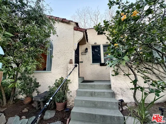 a front view of a house with a tree
