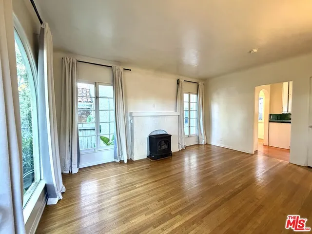 an empty room with wooden floor fireplace and windows