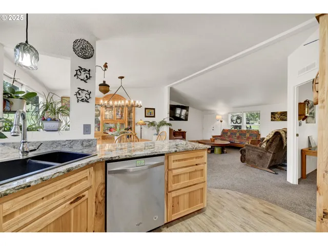 a kitchen with a sink dishwasher a dining table and chairs with wooden floor