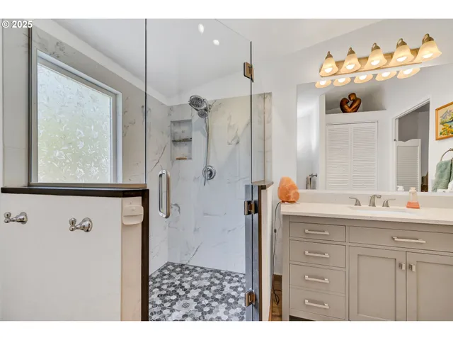a bathroom with a sink a mirror a vanity and a shower