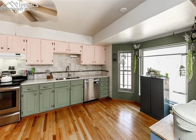 a kitchen with granite countertop a refrigerator a sink dishwasher a stove and white cabinets with wooden floor