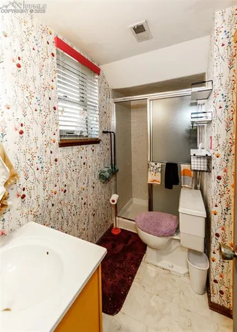 a bathroom with a sink a toilet and shower