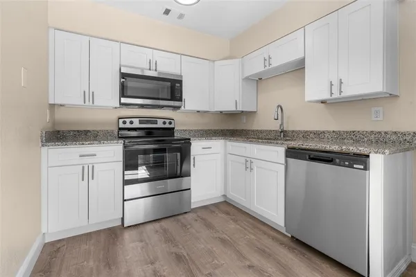 a kitchen with granite countertop white cabinets and stainless steel appliances