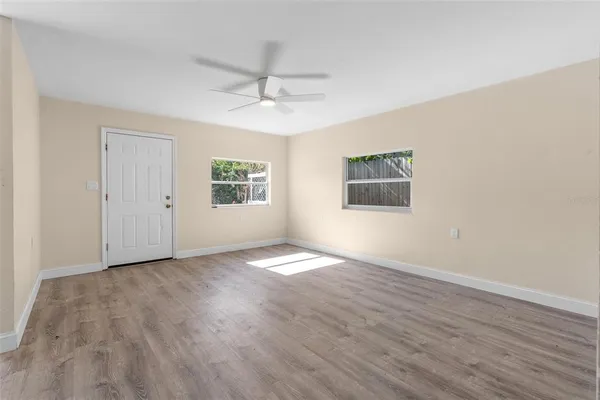 a view of an empty room with a window and wooden floor
