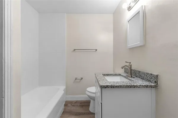 a bathroom with a granite countertop sink a toilet and bathtub