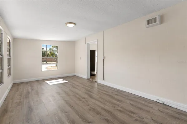 a view of an empty room with wooden floor and a window