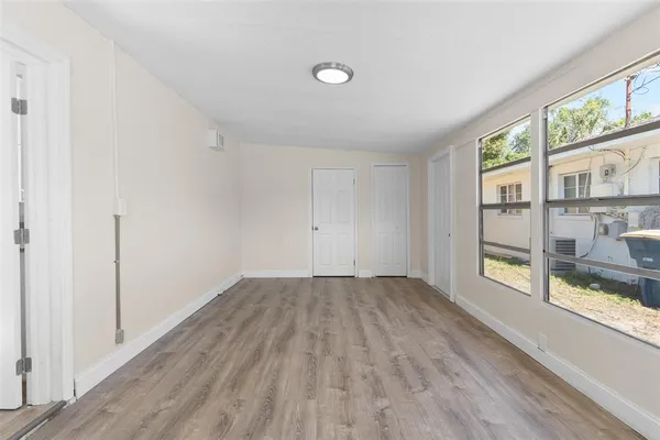 a view of an empty room with wooden floor and a window