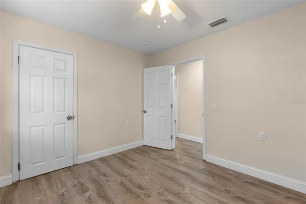 an empty room with wooden floor and a ceiling fan
