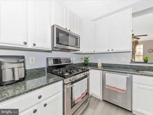 a kitchen with granite countertop white cabinets and stainless steel appliances