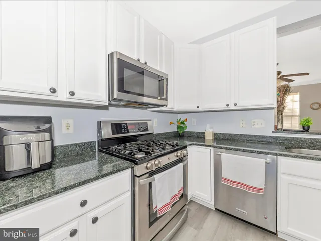 a kitchen with granite countertop white cabinets and stainless steel appliances