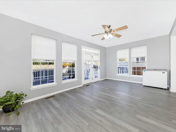 a view of empty room with wooden floor and kitchen view