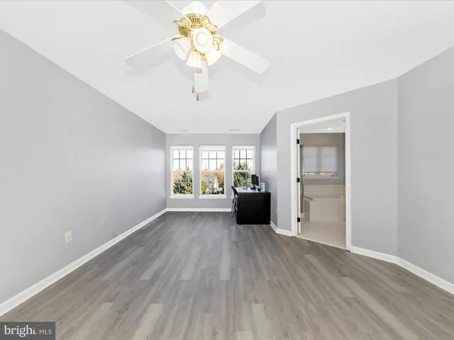 a view of an empty room with a window and a kitchen