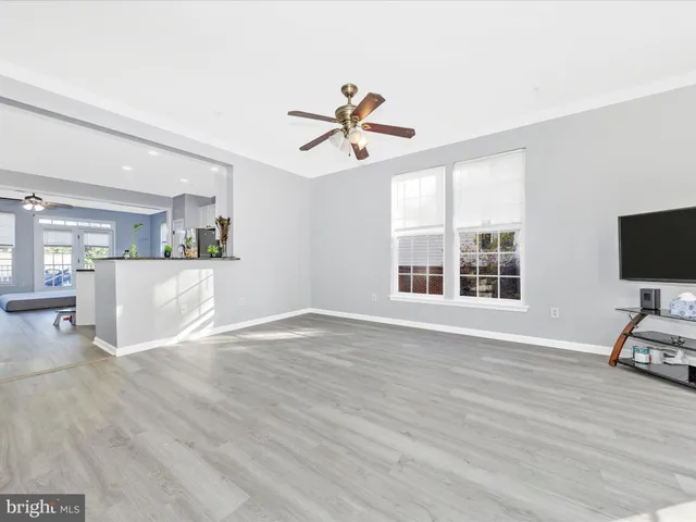 a view of a kitchen and an empty room with wooden floor and windows
