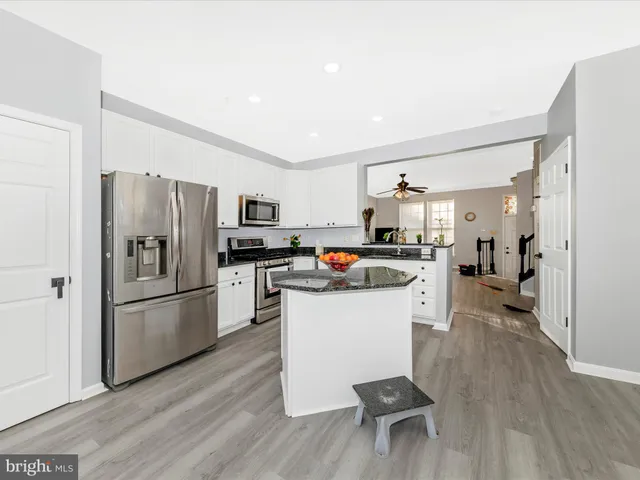 a kitchen with a refrigerator a stove top oven a sink dishwasher and a dining table with wooden floor