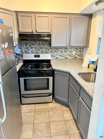 a kitchen with granite countertop a stove sink and cabinets