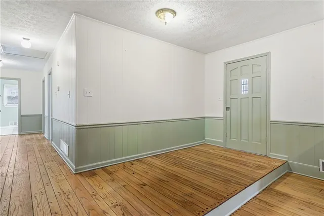 a view of an empty room with wooden floor fireplace and a window