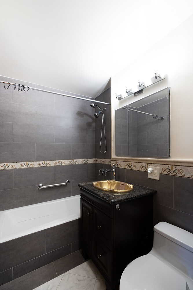 1401 Ocean Avenue, Unit 6H Brooklyn, NY 11230 - Photo 8 of 10 a bathroom with a sink a toilet and mirror