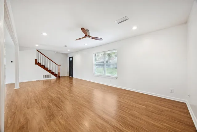 a view of empty room with wooden floor and fan