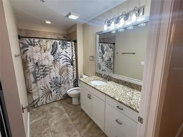 a bathroom with a granite countertop sink a toilet and shower