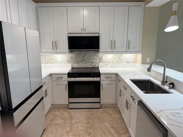 a kitchen with stainless steel appliances granite countertop white cabinets a microwave a sink and a refrigerator