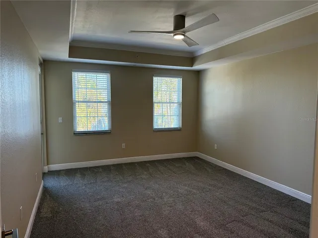 an empty room with ceiling fan and windows
