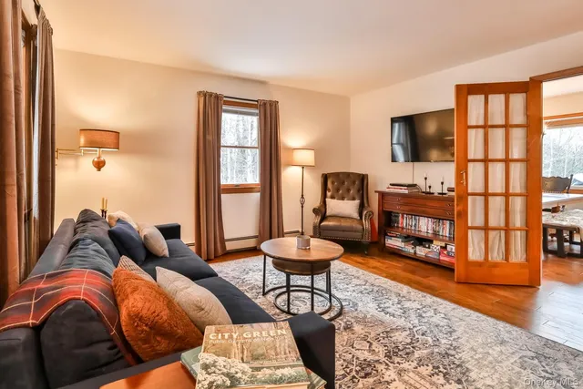 a living room with furniture a rug a flat screen tv and a large window