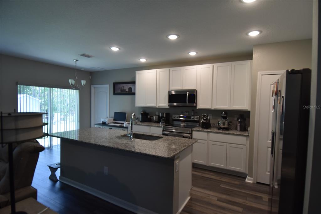 14241 Ravine Avenue Weeki Wachee, FL 34614 - Photo 5 of 48 a kitchen with kitchen island granite countertop a sink a stove a refrigerator cabinets and a dining table