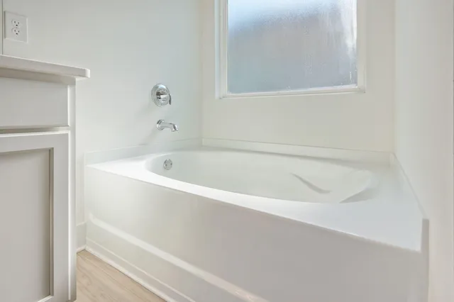 a white bath tub sitting next to a white cabinet