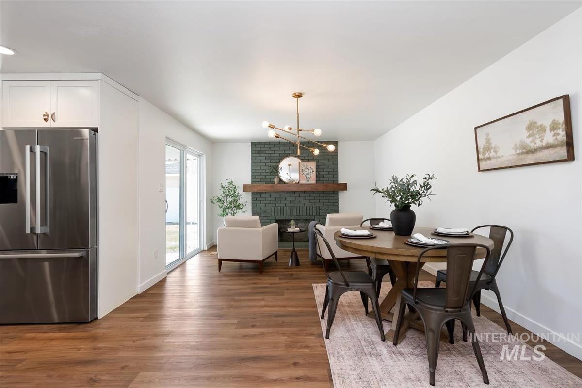 2217 North Middlefield Road Boise, ID 83704 - Photo 17 of 34 Open-concept living area featuring wood-finish flooring, a contemporary fireplace with a dark brick surround, and a brass-finish linear chandelier