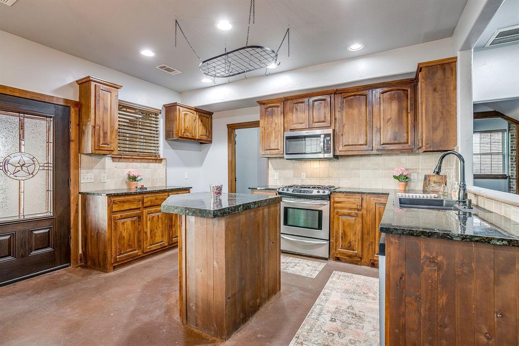 2220 Lazy Bend Road Millsap, TX 76066 - Photo 20 of 36 a kitchen with stainless steel appliances granite countertop wooden cabinets a sink dishwasher a stove and a refrigerator with wooden cabinets