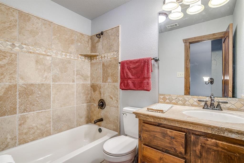 2220 Lazy Bend Road Millsap, TX 76066 - Photo 31 of 36 a bathroom with a sink a toilet a mirror a vanity and bathtub