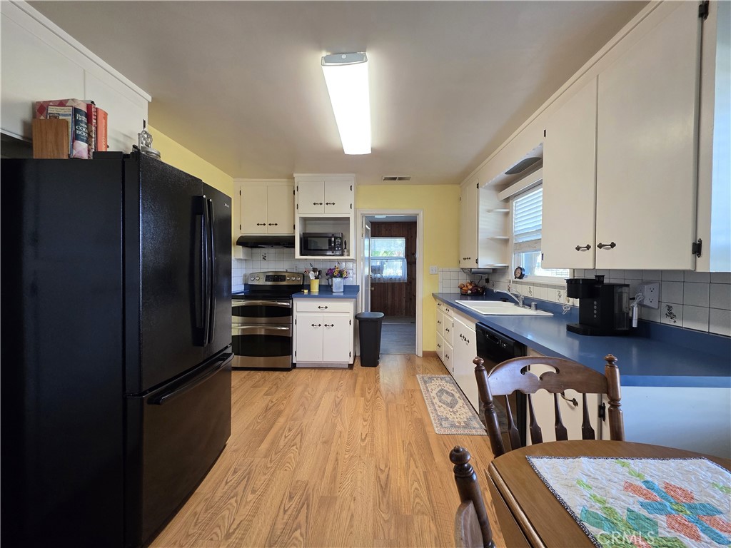 23773 River Road Corning, CA 96021 - Photo 3 of 64 a kitchen with stainless steel appliances granite countertop a refrigerator a stove top oven a sink dishwasher and white cabinets with wooden floor